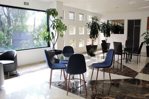 A modern conference room with a glass table, blue chairs, and potted plants. - Hotel Aqueronte (Ixtapaluca)