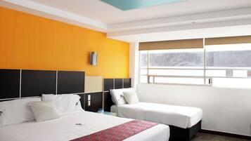 Habitación de hotel con dos camas, un ventanal con persianas y un techo con detalles azules.