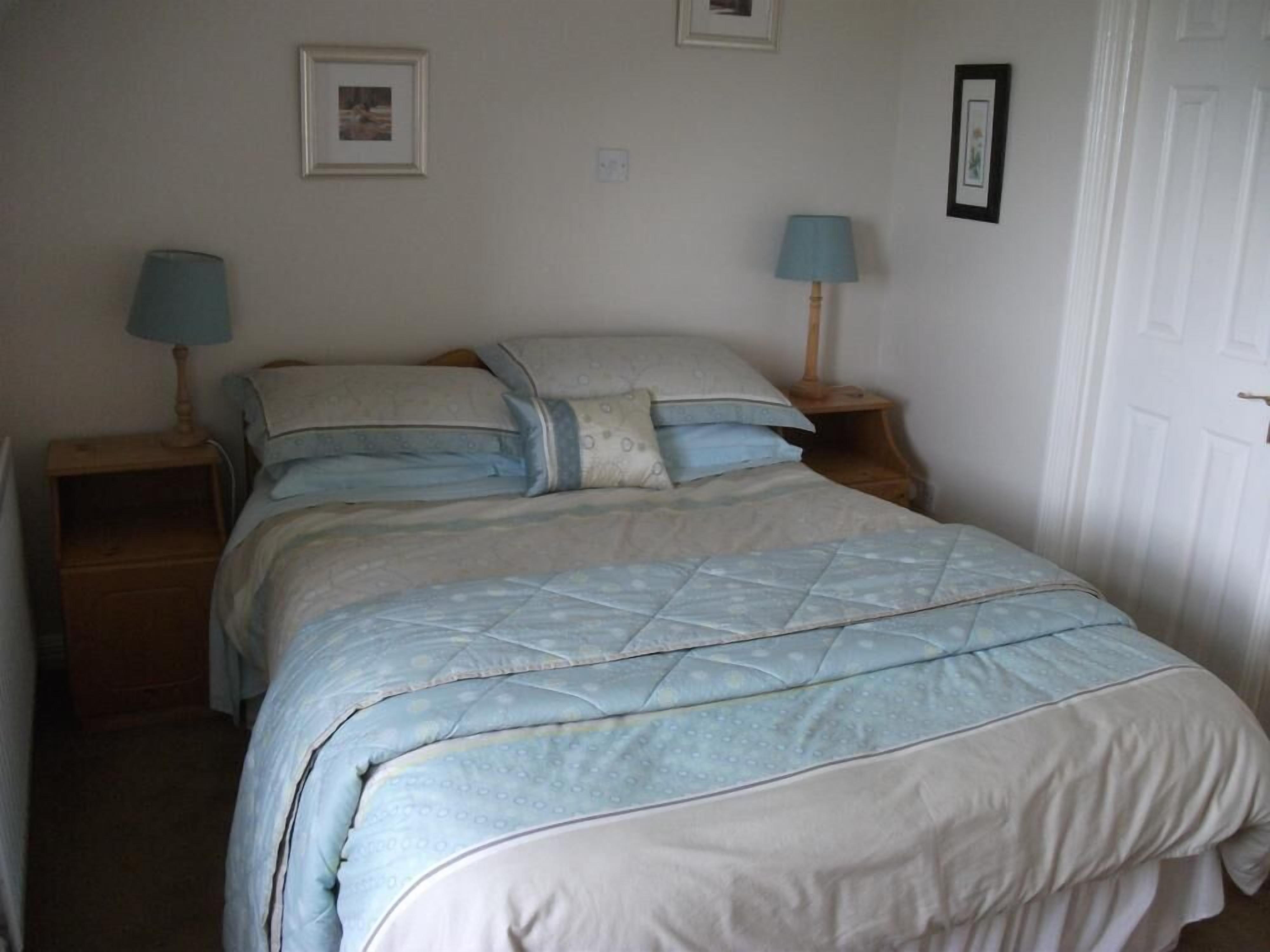 A bedroom with a bed, two bedside tables, and two lamps.