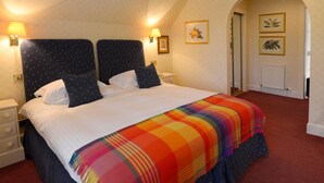 A hotel room with a large bed, two bedside tables, and two wall-mounted lamps. - Factors Inn & Cottage (Fort William)
