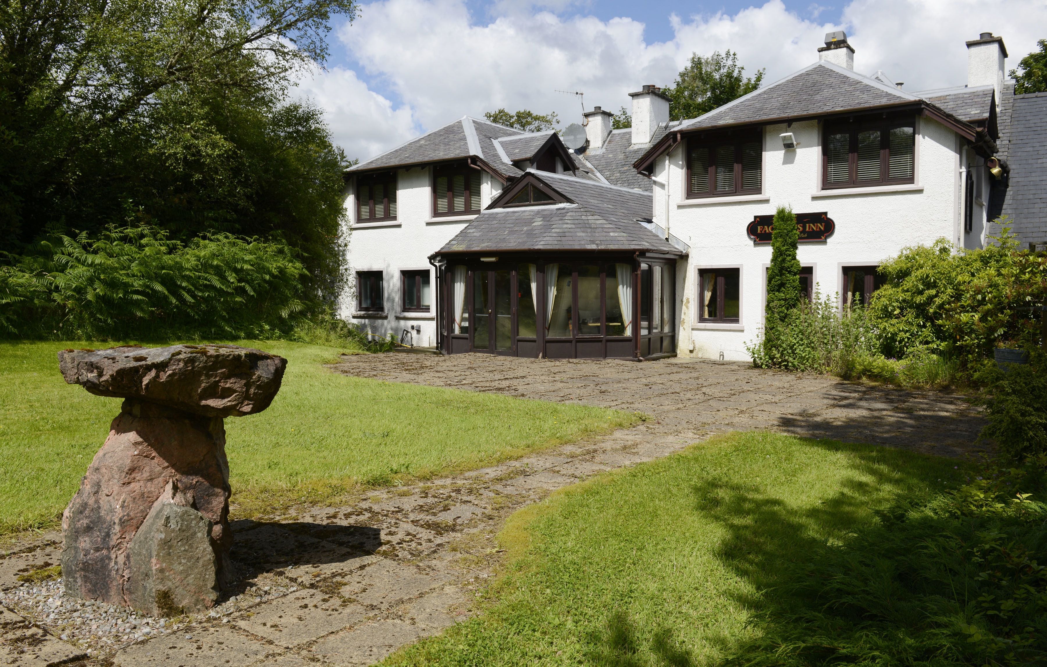 A traditional building with a sign reading "FACHS INN" and a stone structure in the foreground.