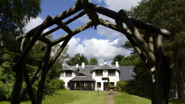 A traditional white building with a stone pathway leading to a wooden archway. - Factors Inn & Cottage (Fort William)