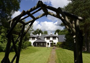 A traditional white building with a stone pathway leading to a wooden archway.