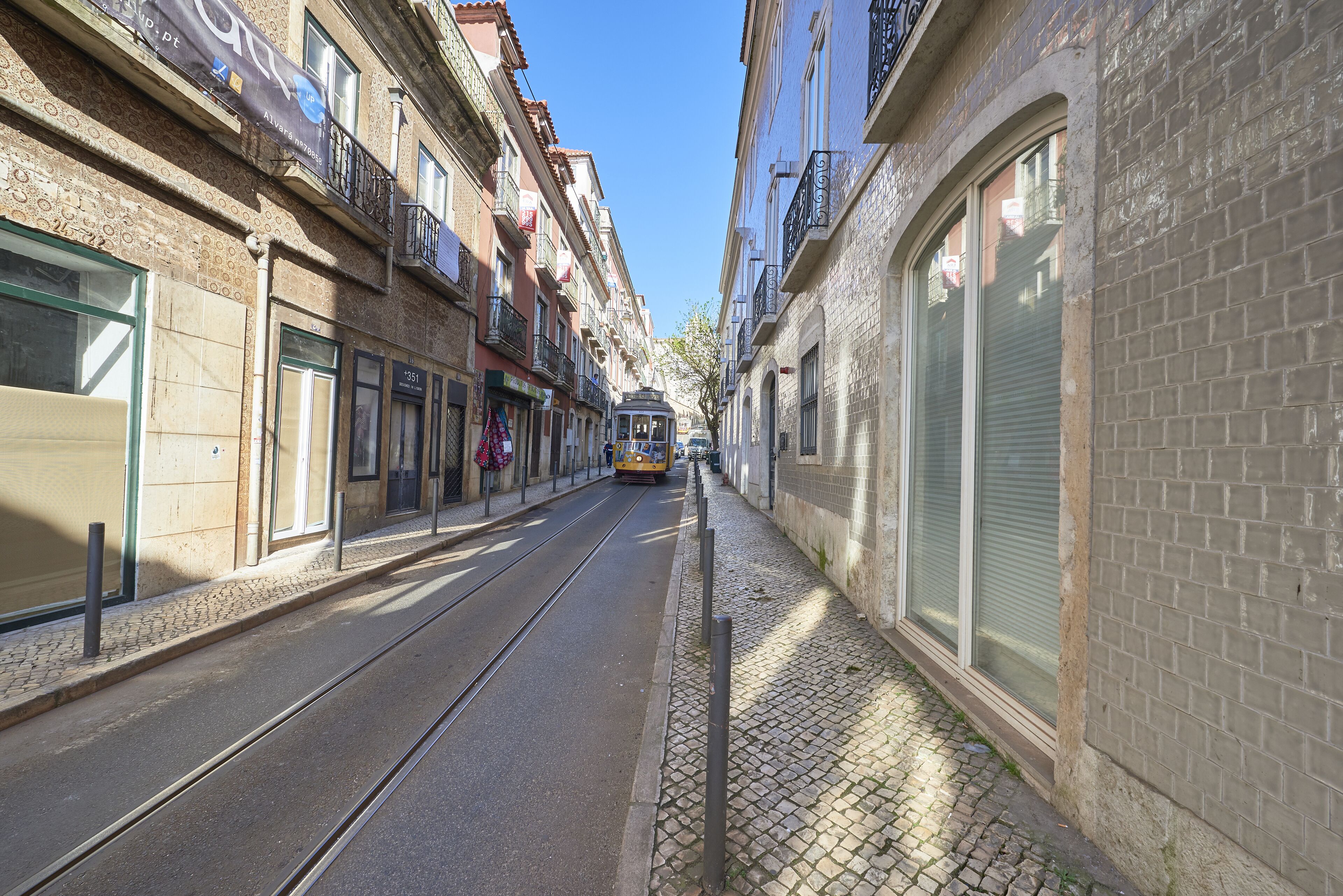 Une rue étroite, avec un tramway, des bâtiments de chaque côté et un chemin pavé.