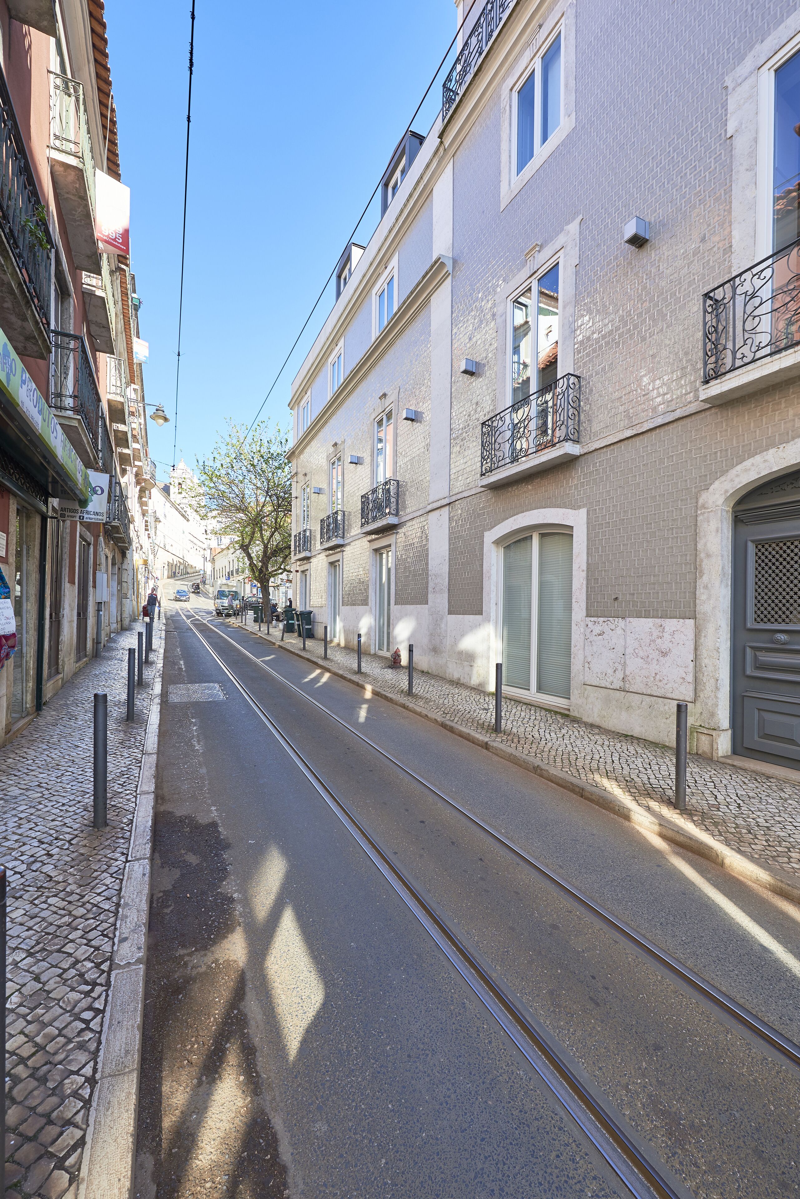 Une rue bordée de bâtiments des deux côtés, une voie ferrée pour tramway et un ciel dégagé.