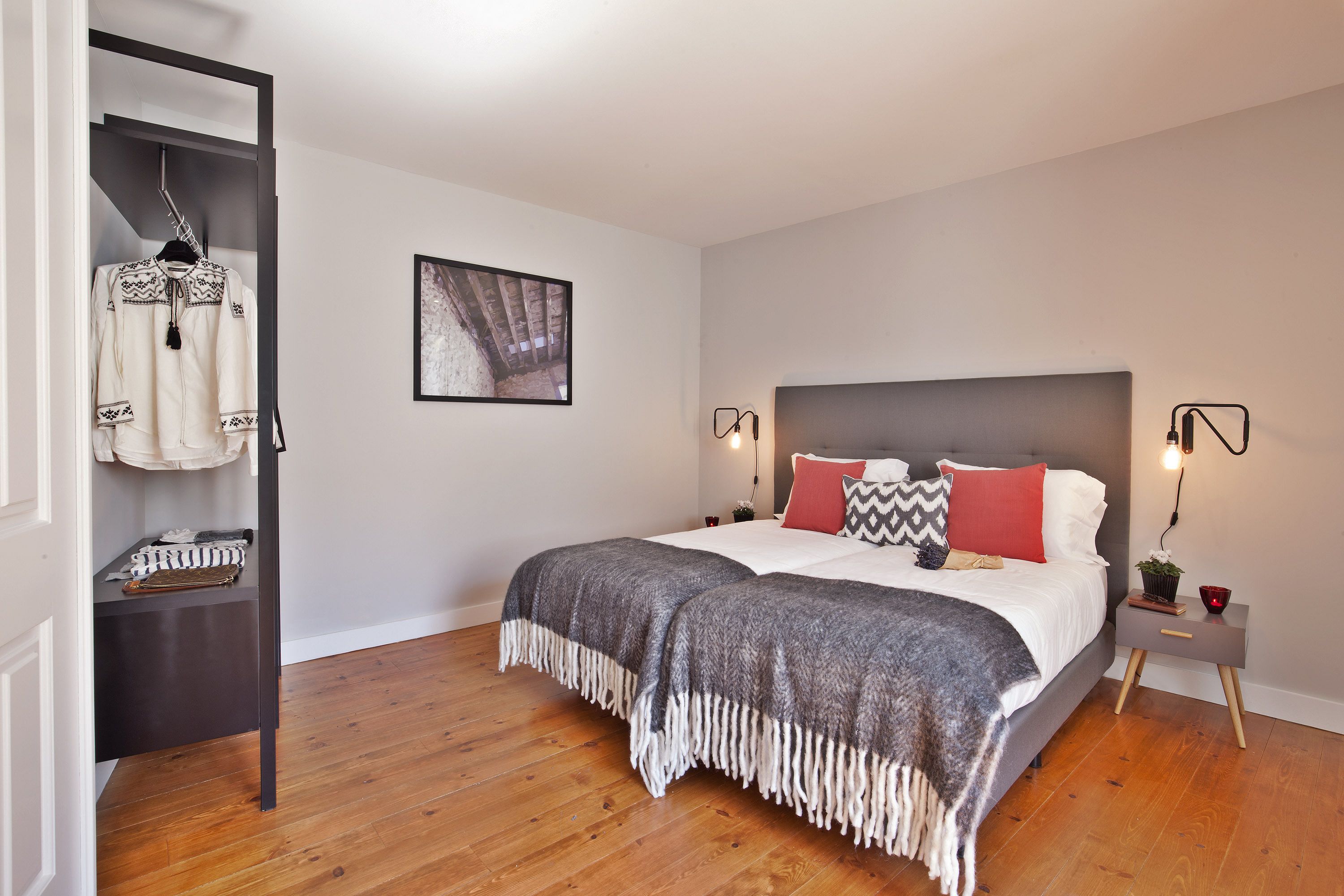 Quarto com cama, mesas de cabeceira, guarda-roupa e um quadro emoldurado na parede.