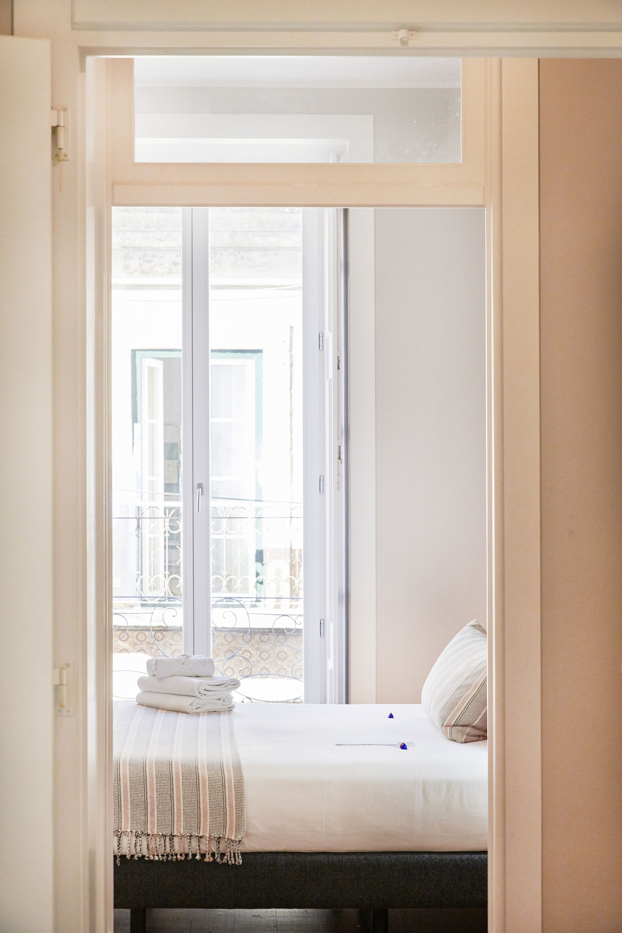 Una camera da letto con un letto, un comodino e vista su un balcone esterno.
