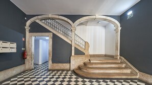 Een trap met een zwart-wit geruite vloer en een brandblusser aan de muur.