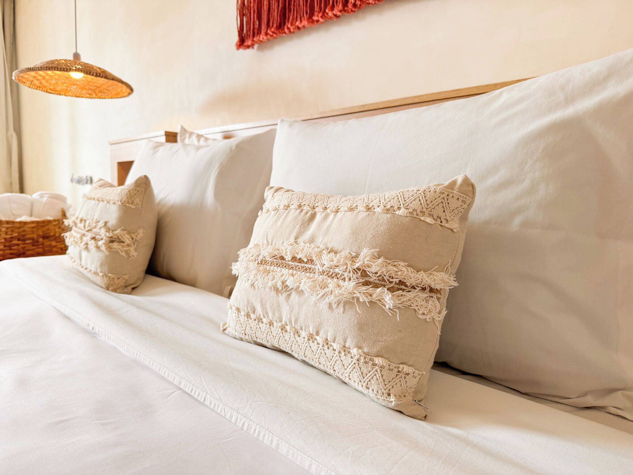 Un lit bien fait, avec du linge de lit blanc et des coussins décoratifs.