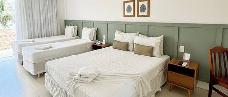 A hotel room with two beds, a wooden nightstand, a chair, and a window with curtains.