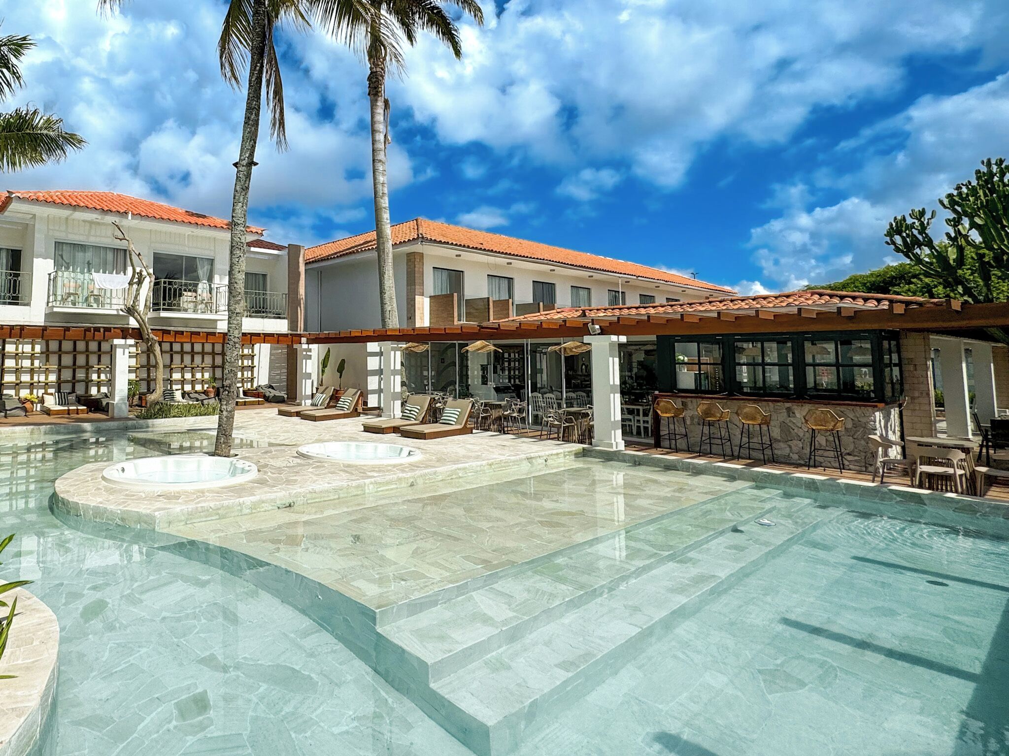 A resort with a large pool, outdoor seating, and a bar area.