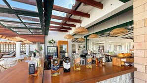 A bar area with wooden beams, wicker pendant lights, and a variety of liquor bottles. - Hotel Premium Recanto da Passagem (Cabo Frio)