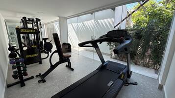 A modern gym with a treadmill, weight machines, and a bench.
