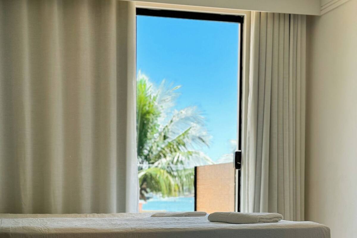 A hotel room with a bed, a view of palm trees, and a door leading outside.