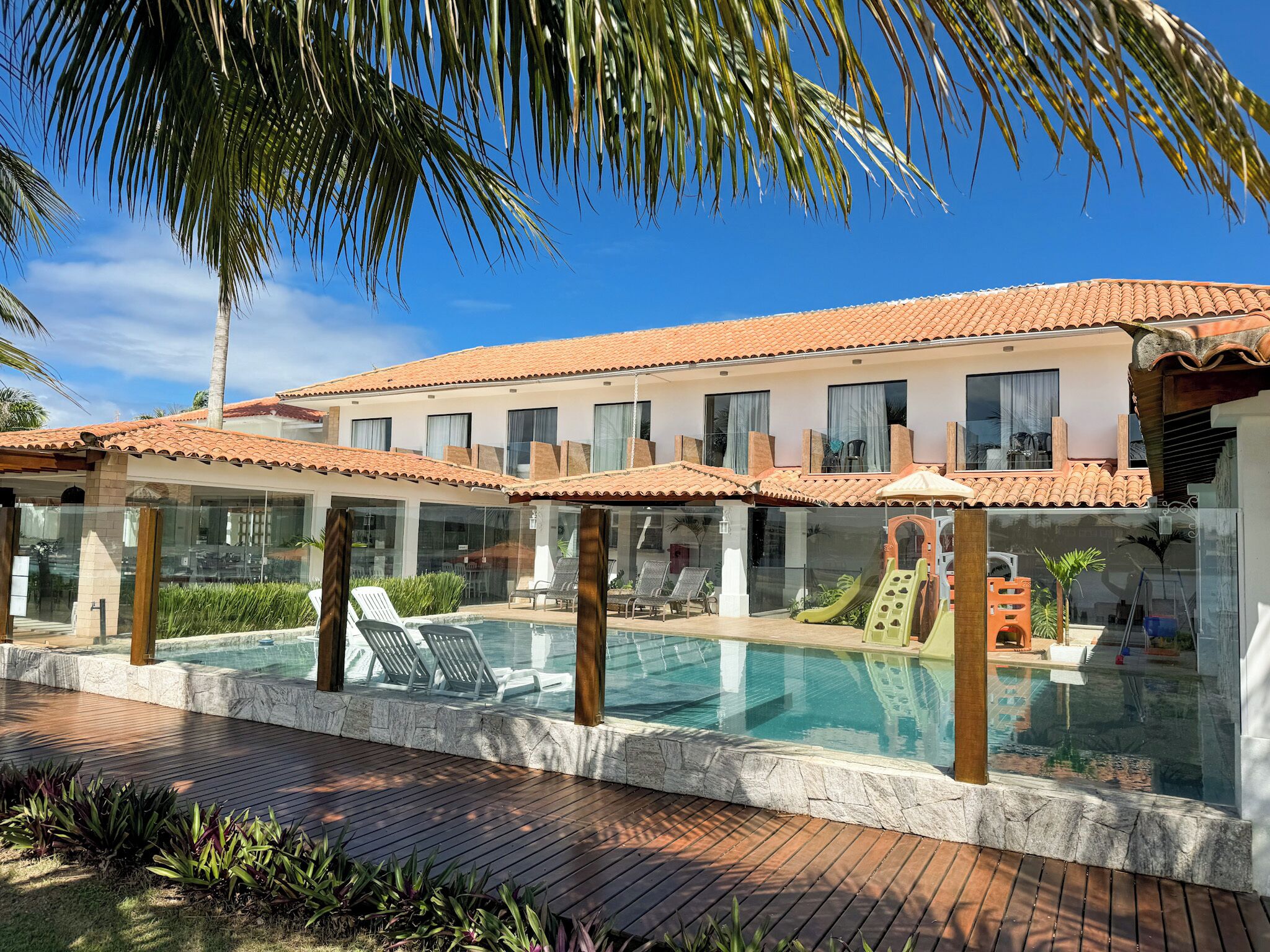 A resort with a swimming pool, lounge chairs, and a palm tree.