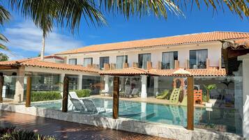 A resort with a swimming pool, lounge chairs, and a palm tree.