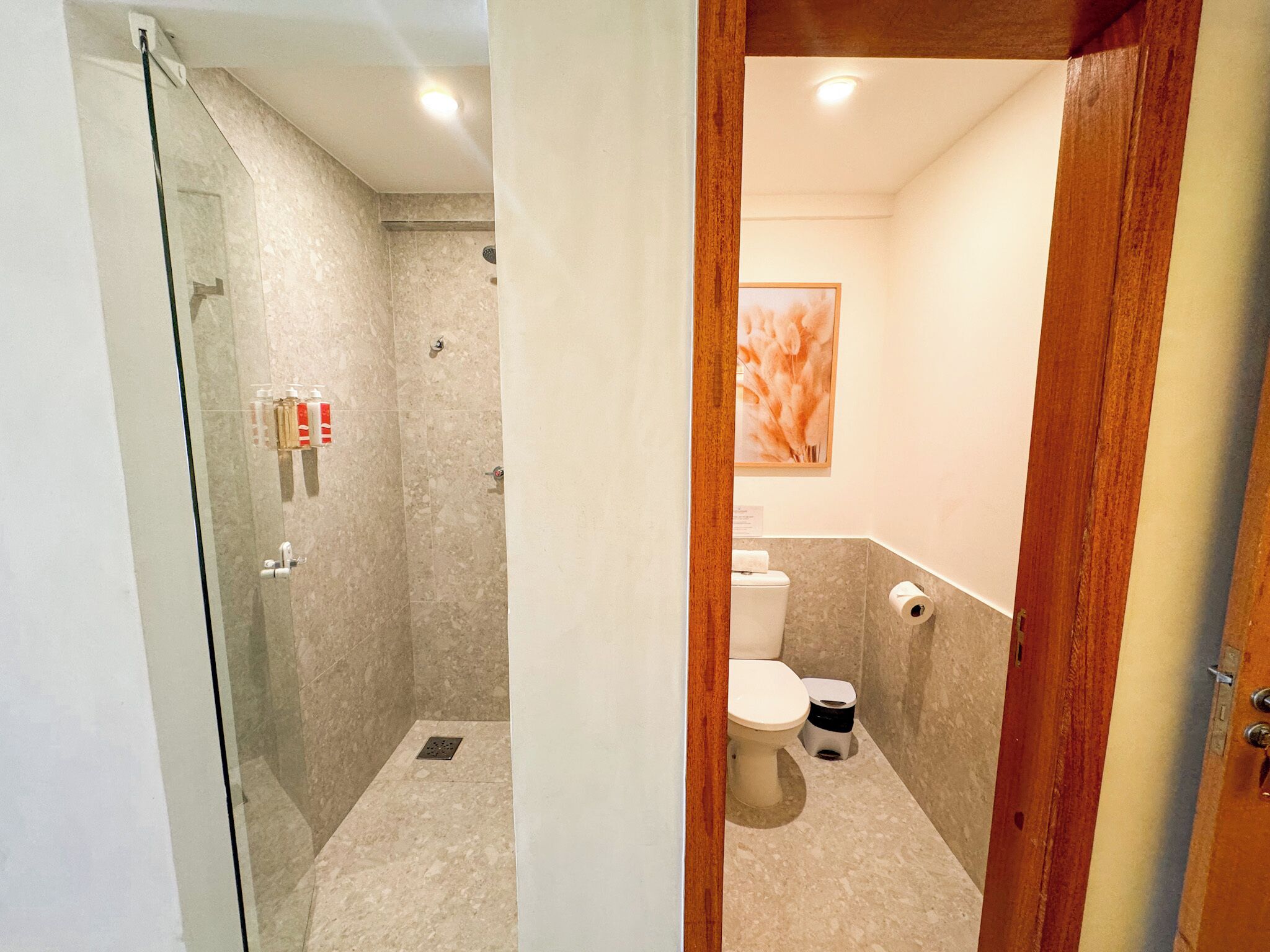 A bathroom with a glass shower enclosure, a toilet, and a sink.