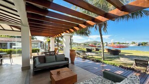 An outdoor patio with a wooden pergola, seating area, and a view of the water. - Hotel Premium Recanto da Passagem (Cabo Frio)