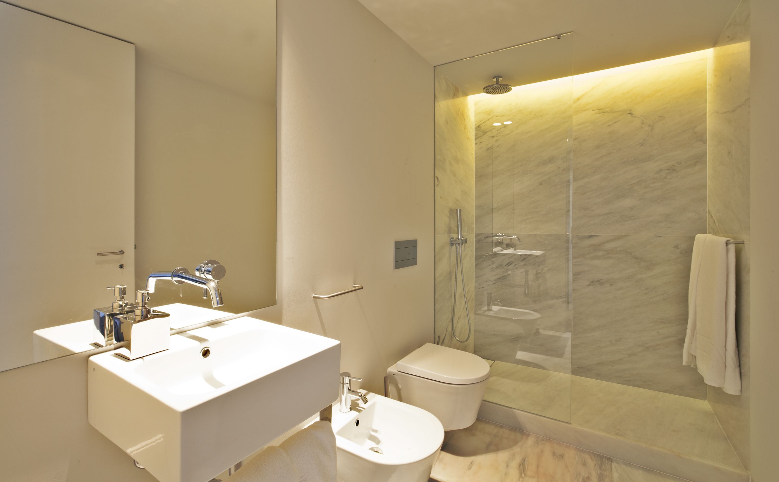 A modern bathroom with a white sink, toilet, and glass-enclosed shower.
