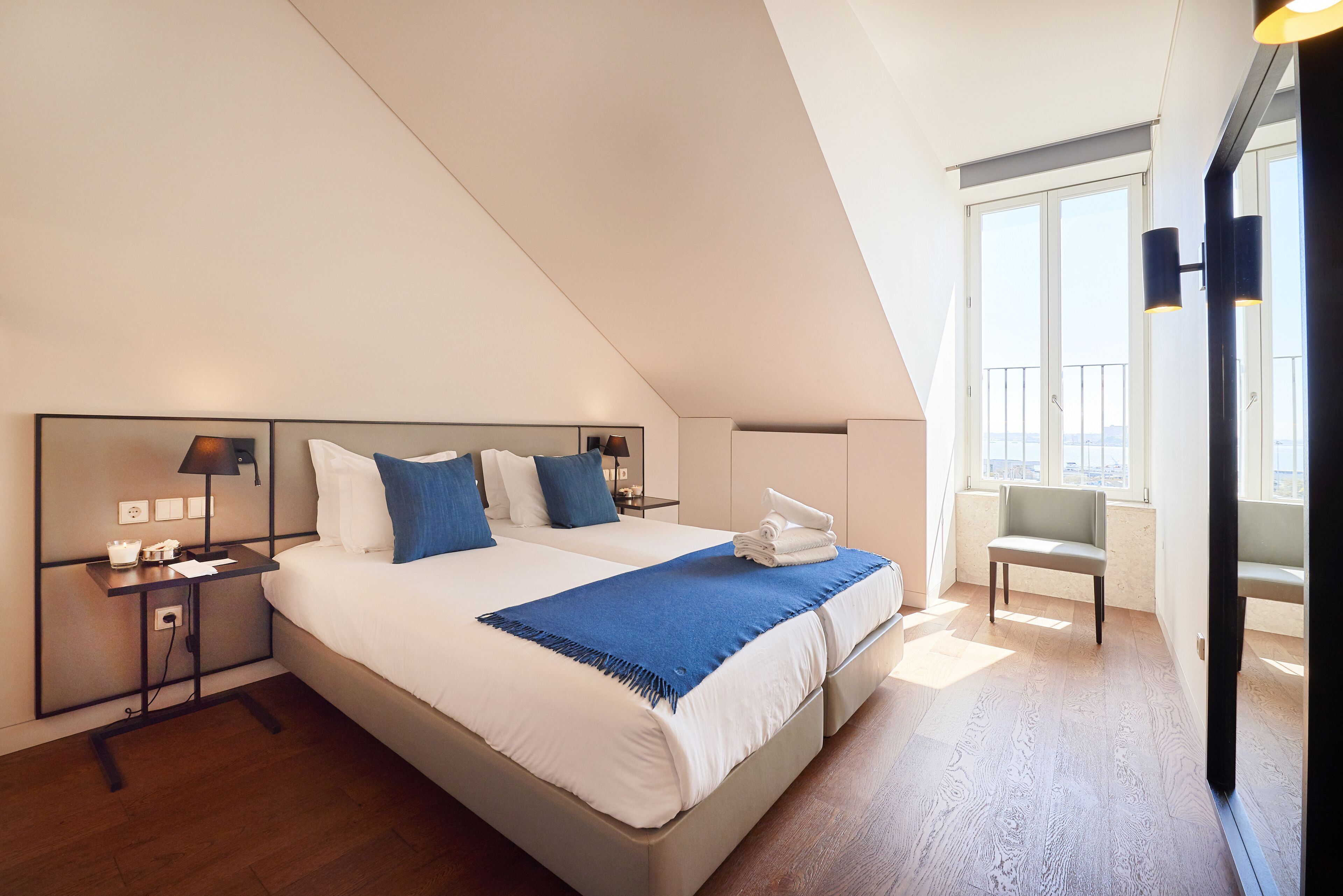 A modern hotel room with a large bed, two bedside tables, a desk, and a chair.