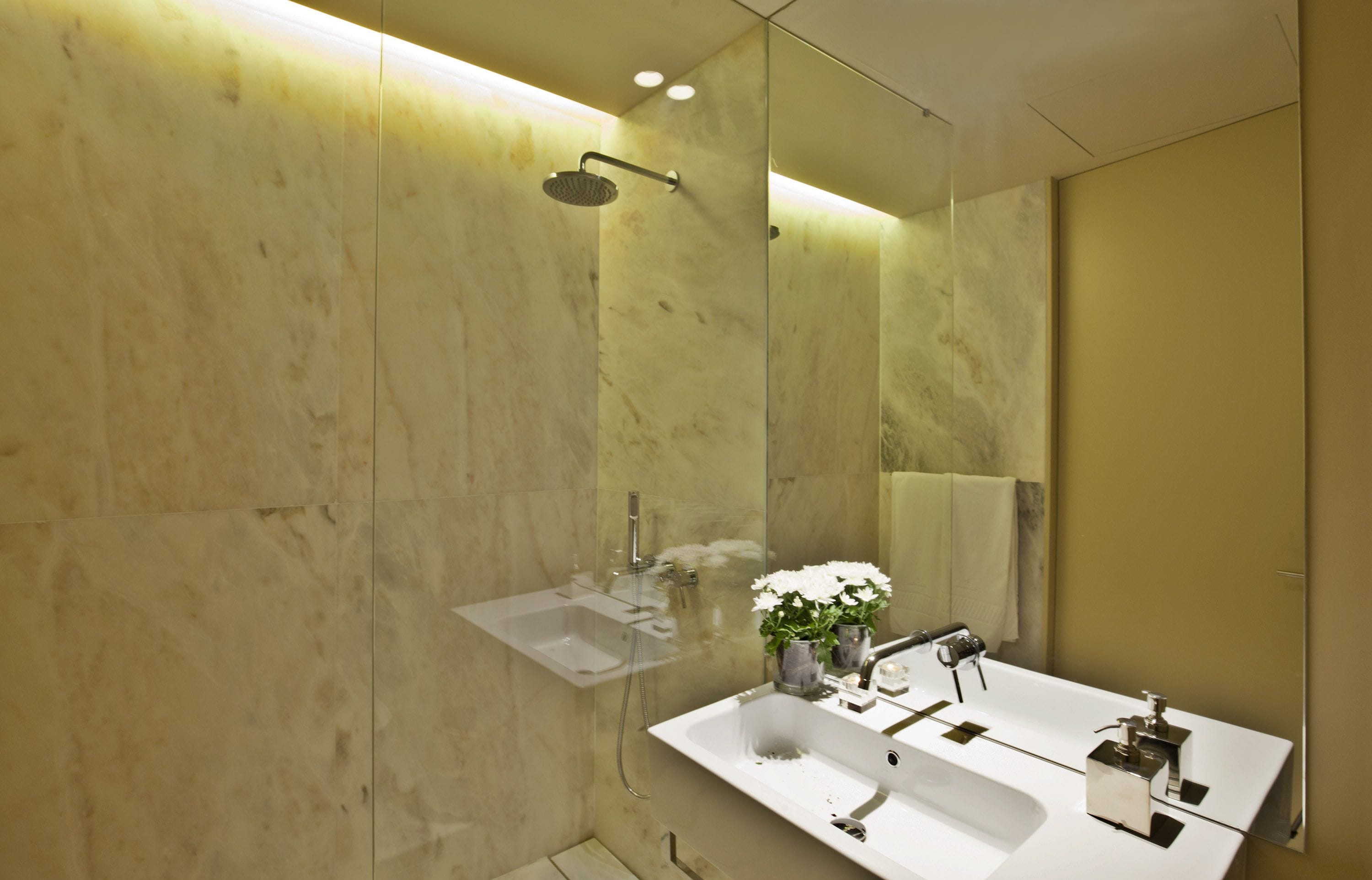 A modern bathroom with a double sink, a glass shower enclosure, and a large mirror.