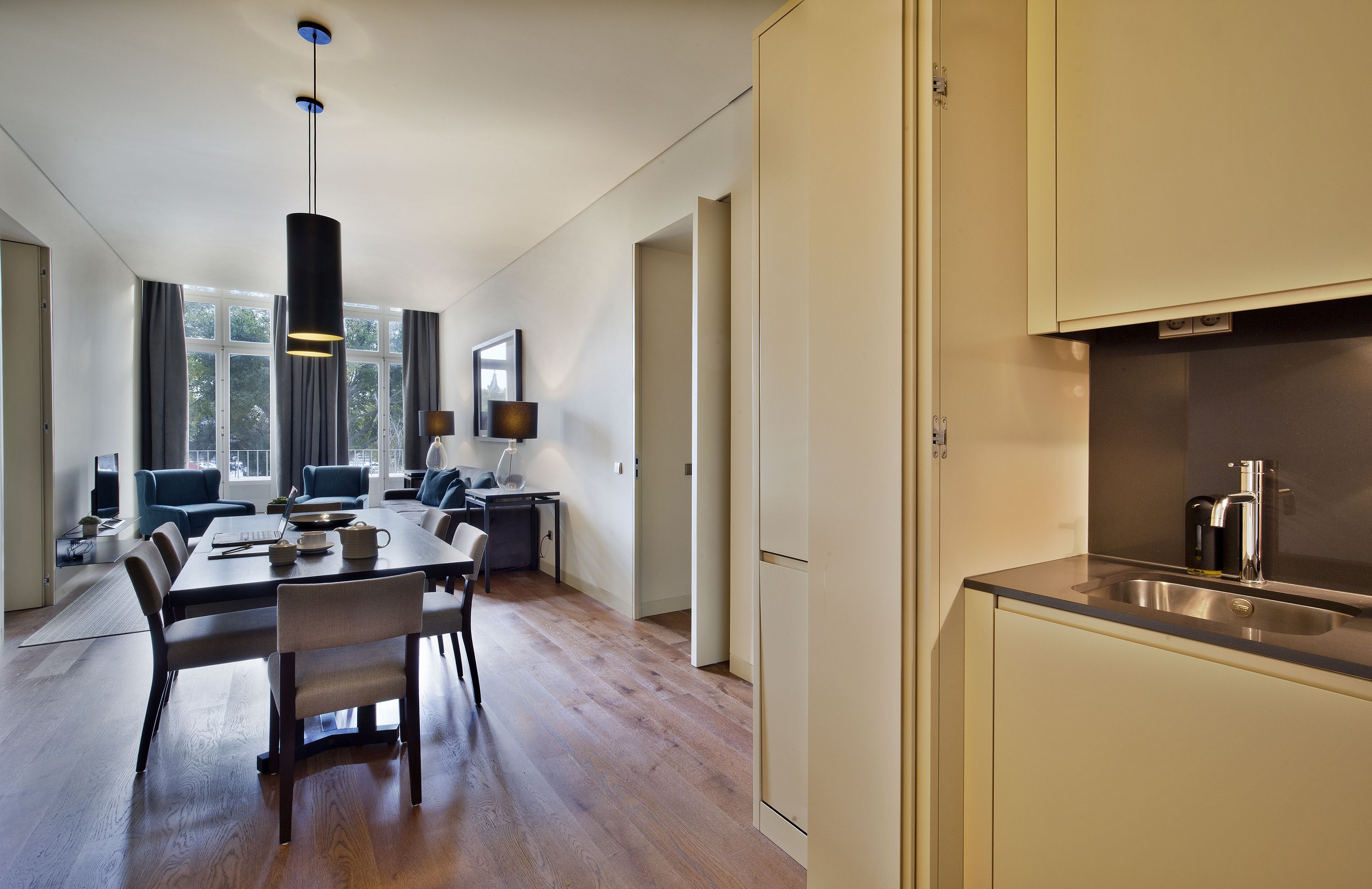 Una cocina moderna con un lavaplatos de acero inoxidable y un comedor con mesa y sillas de madera.