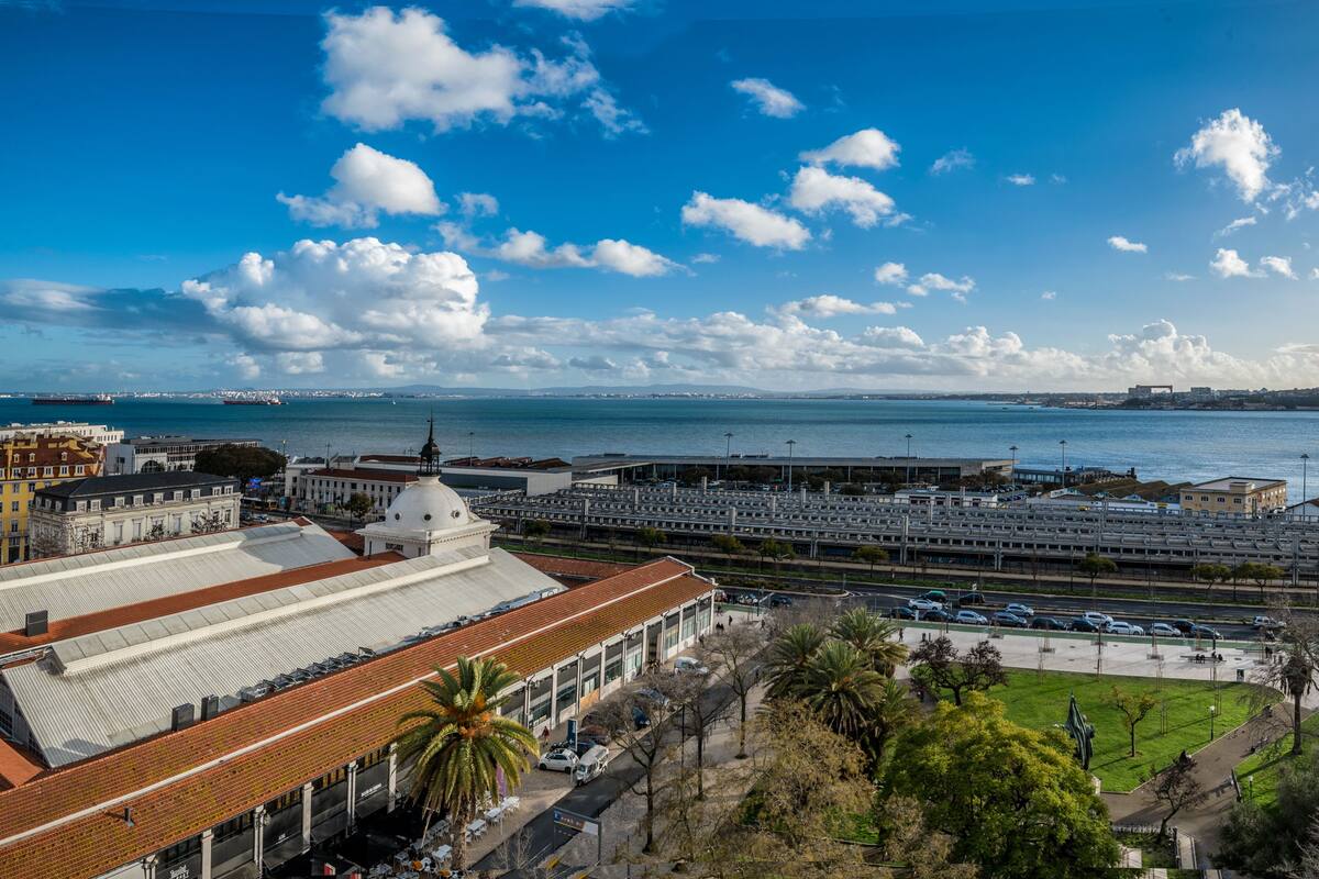 A coastal cityscape with a prominent train station, waterfront buildings, and a clear sky.