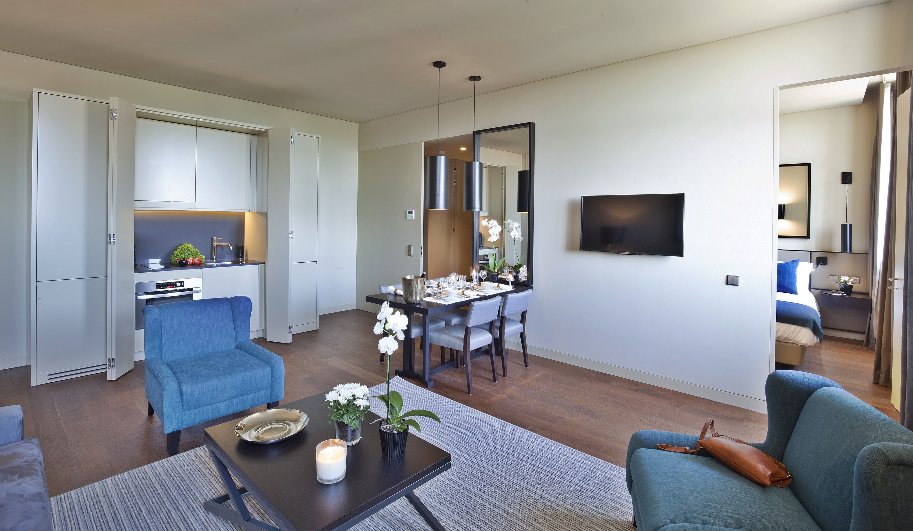 A modern living room with a dining area, a kitchen, and a bedroom.