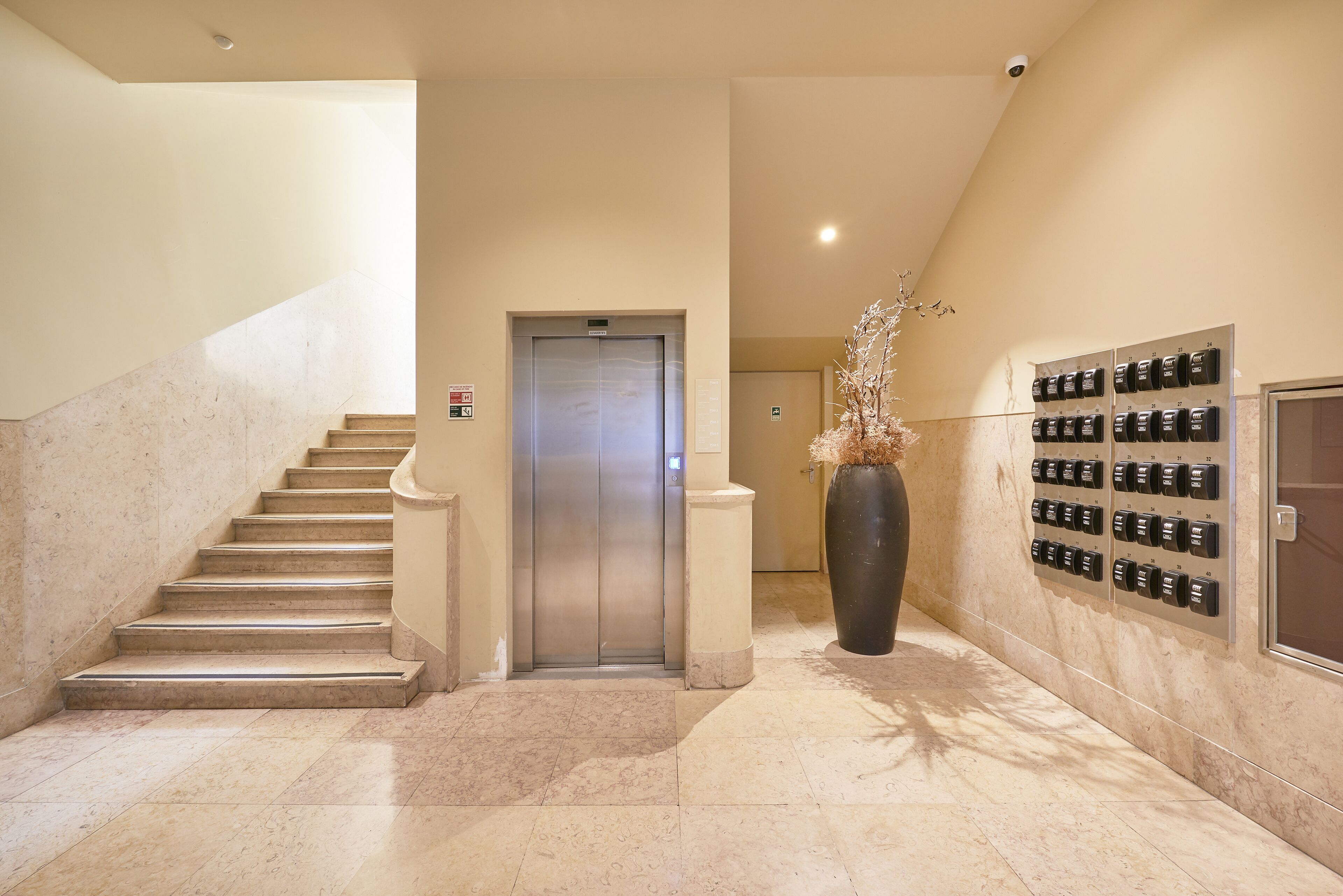 A hotel lobby with a marble staircase, an elevator, and a wall-mounted keycard system.