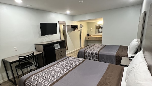 A hotel room with two beds, a desk, a chair, a TV, and a bathroom visible in the background. - Continental Inn & Suites Nacogdoches TX / SFA  University/Downtown (Nacogdoches)