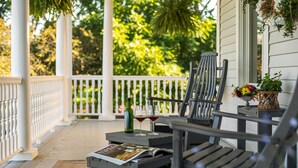 A porch with two chairs, a table with a bottle and glasses, and a magazine. - The Jacqueline House of Wilmington (New Wilmington)
