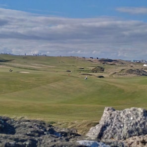 A golf course with bunkers and a city skyline in the background. - Aberdeen Lighthouse Cottages (Aberdeen)