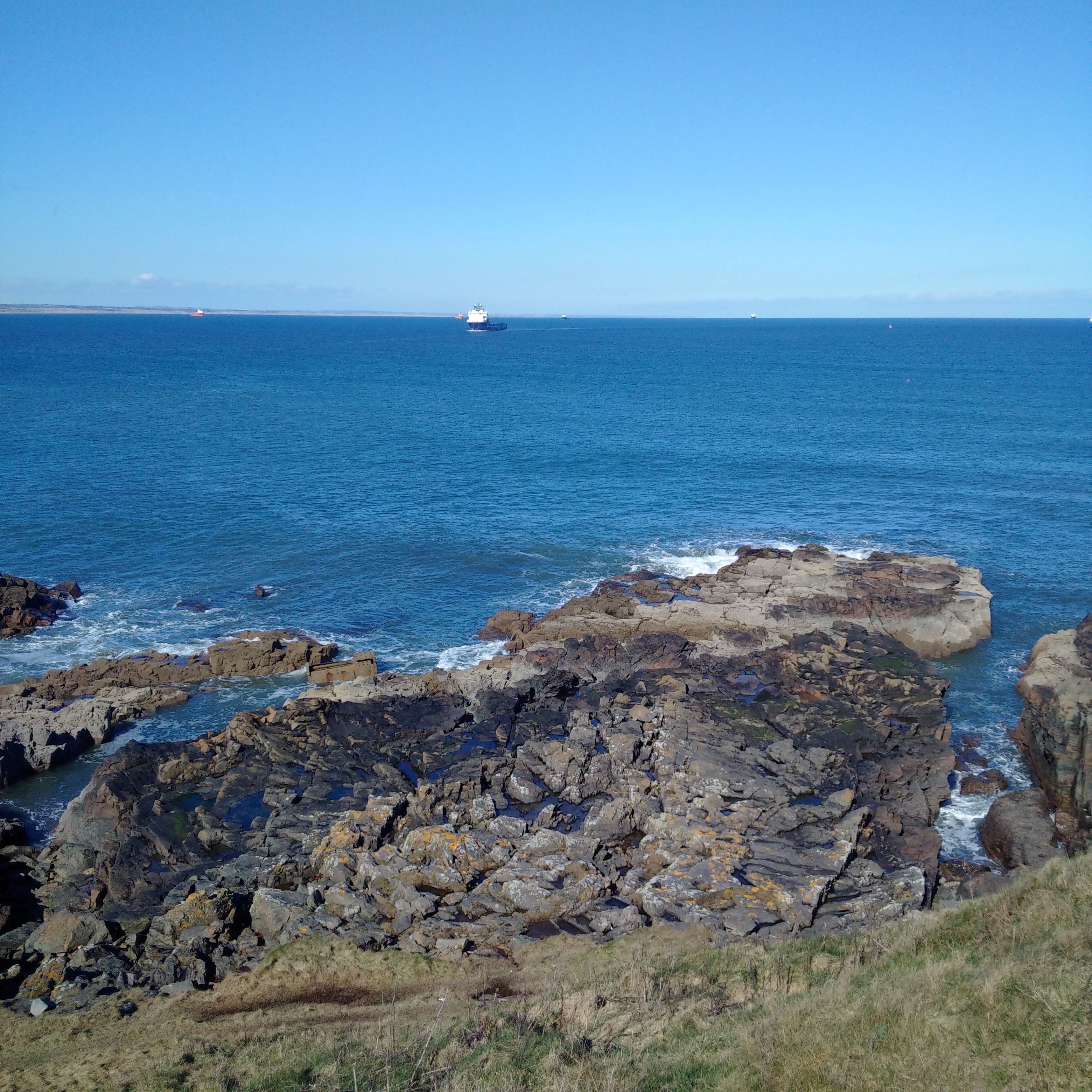 A coastal landscape with rocky terrain and the ocean.