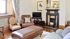 A living room with a fireplace, a television, and a comfortable seating area. - Aberdeen Lighthouse Cottages (Aberdeen)