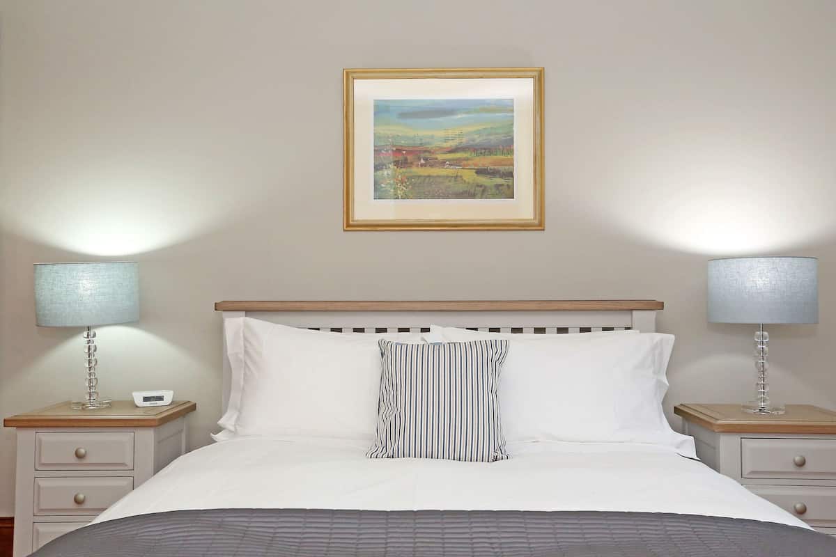 Cozy retreat with a centered bed, framed artwork, and bedside lamps.
