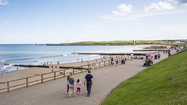 A coastal promenade with a wooden walkway, grassy areas, and a view of the sea. - Aberdeen Lighthouse Cottages (Aberdeen)