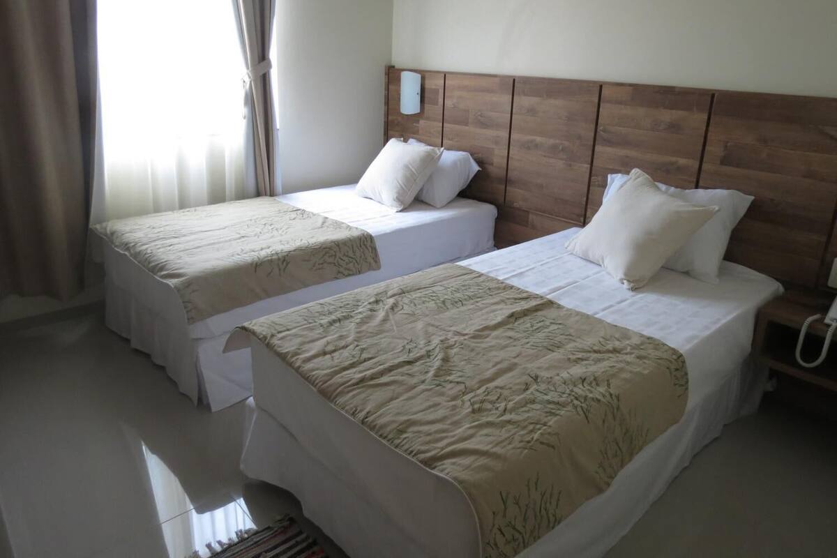 Habitación de hotel con dos camas, cabecera de madera y teléfono en la mesita de noche.