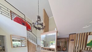 Ein geräumiger, gut beleuchteter Innenraum mit hoher Decke, einer Kristallleuchter, einem Empfangstresen und einer Treppe zu einer oberen Ebene.