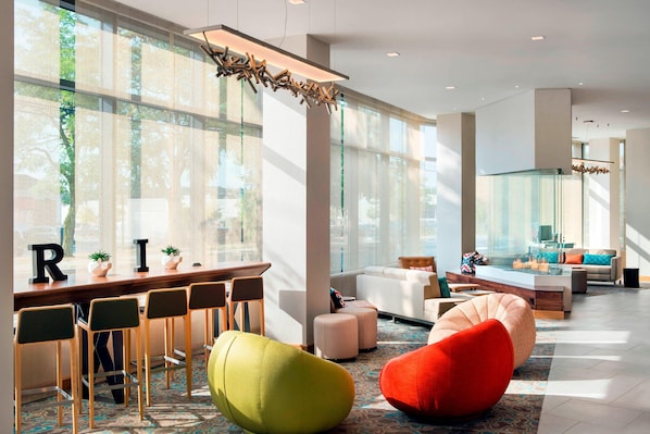 A modern hotel lobby with a bar area, seating, and large windows. - Residence Inn by Marriott Boston Watertown (Watertown)