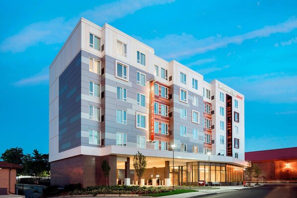 A multi-story hotel with a modern design, featuring a prominent entrance with glass doors and a well-lit facade. - Residence Inn by Marriott Boston Watertown (Watertown)