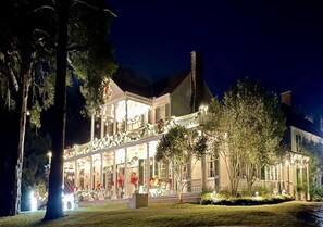 A large, well-lit building with a covered porch and multiple windows, surrounded by trees and well-maintained lawns. - Linden Historic Bed & Breakfast (Natchez)
