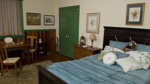 A bedroom with a bed, a desk, a chair, a dresser, and a green door. - The Tinder Guest House (Ashland)