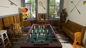 A room with a foosball table, wooden furniture, and various sports equipment on the walls. - The Tinder Guest House (Ashland)
