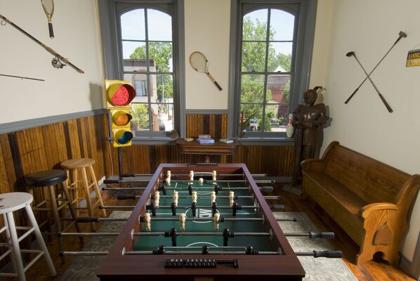 A room with a foosball table, wooden furniture, and various sports equipment on the walls. - The Tinder Guest House (Ashland)