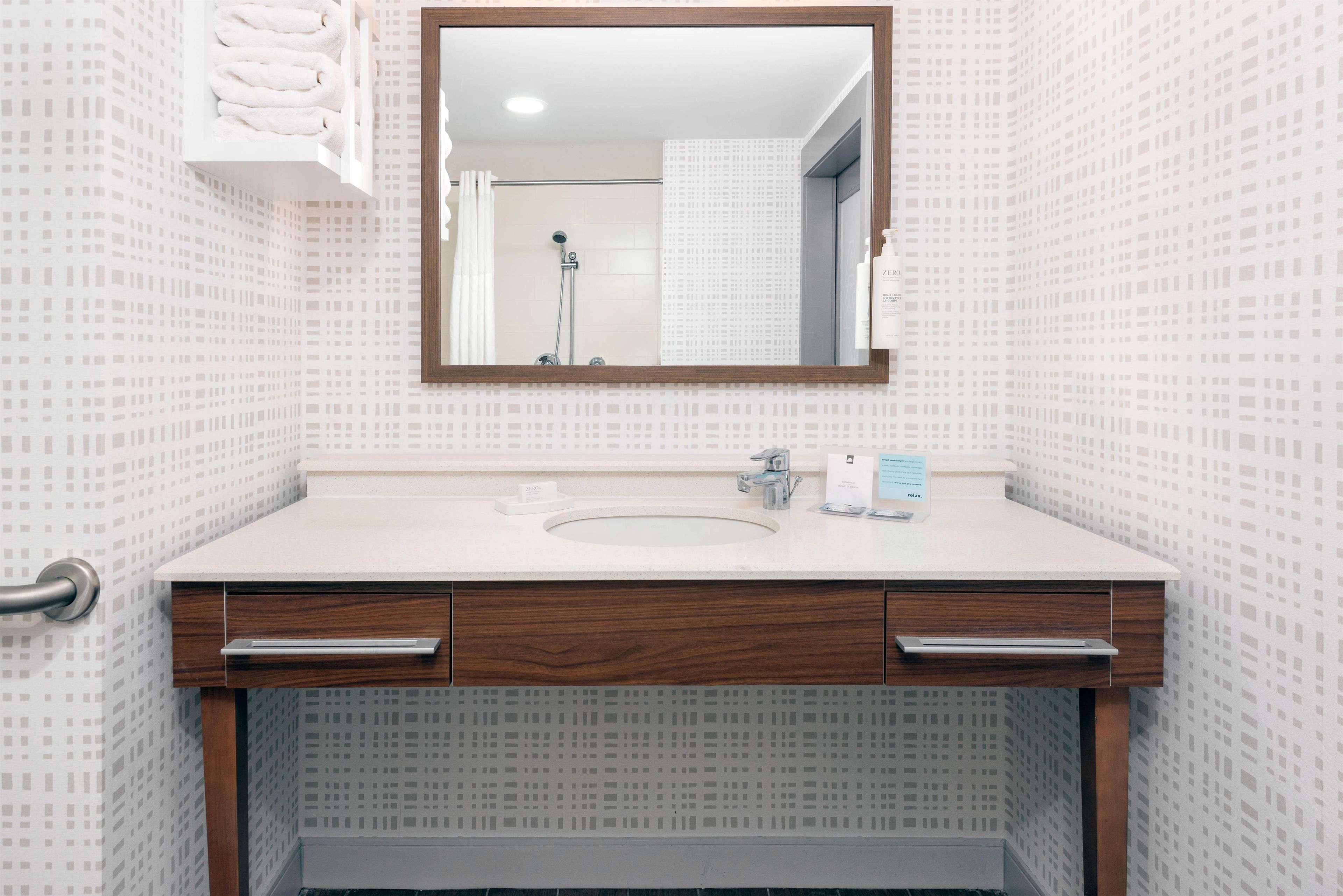 Une salle de bain avec un lavabo blanc, un meuble-lavabo en bois et un miroir.