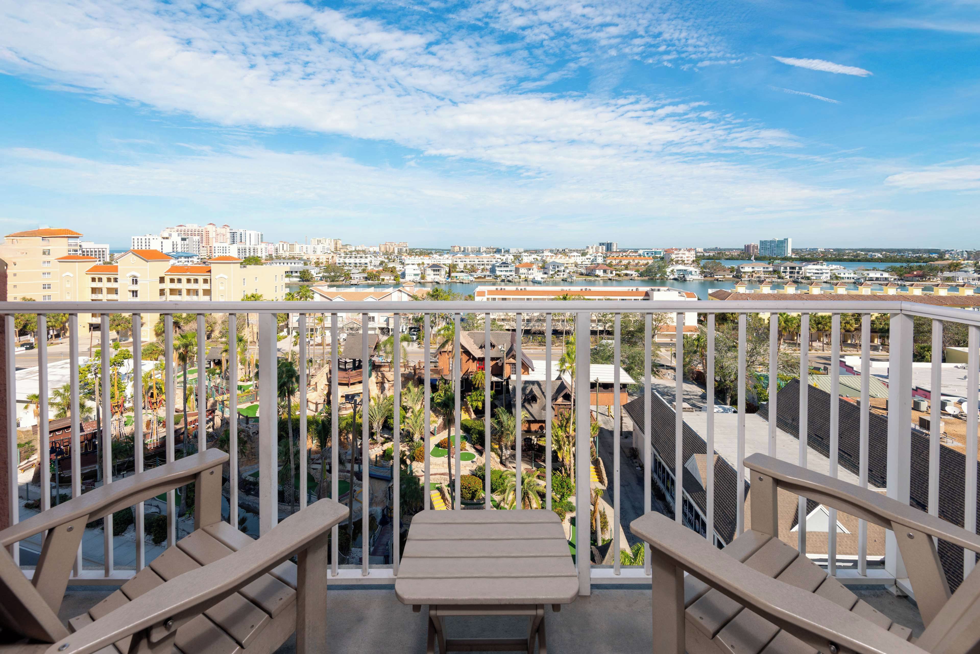 Ein Balkon mit Blick auf eine Stadtlandschaft, darunter Gebäude und ein Gewässer.