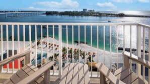 A balcony with a view of a beach, a pool, and a bridge in the distance. - Hampton Inn & Suites Clearwater Beach (Clearwater Beach)