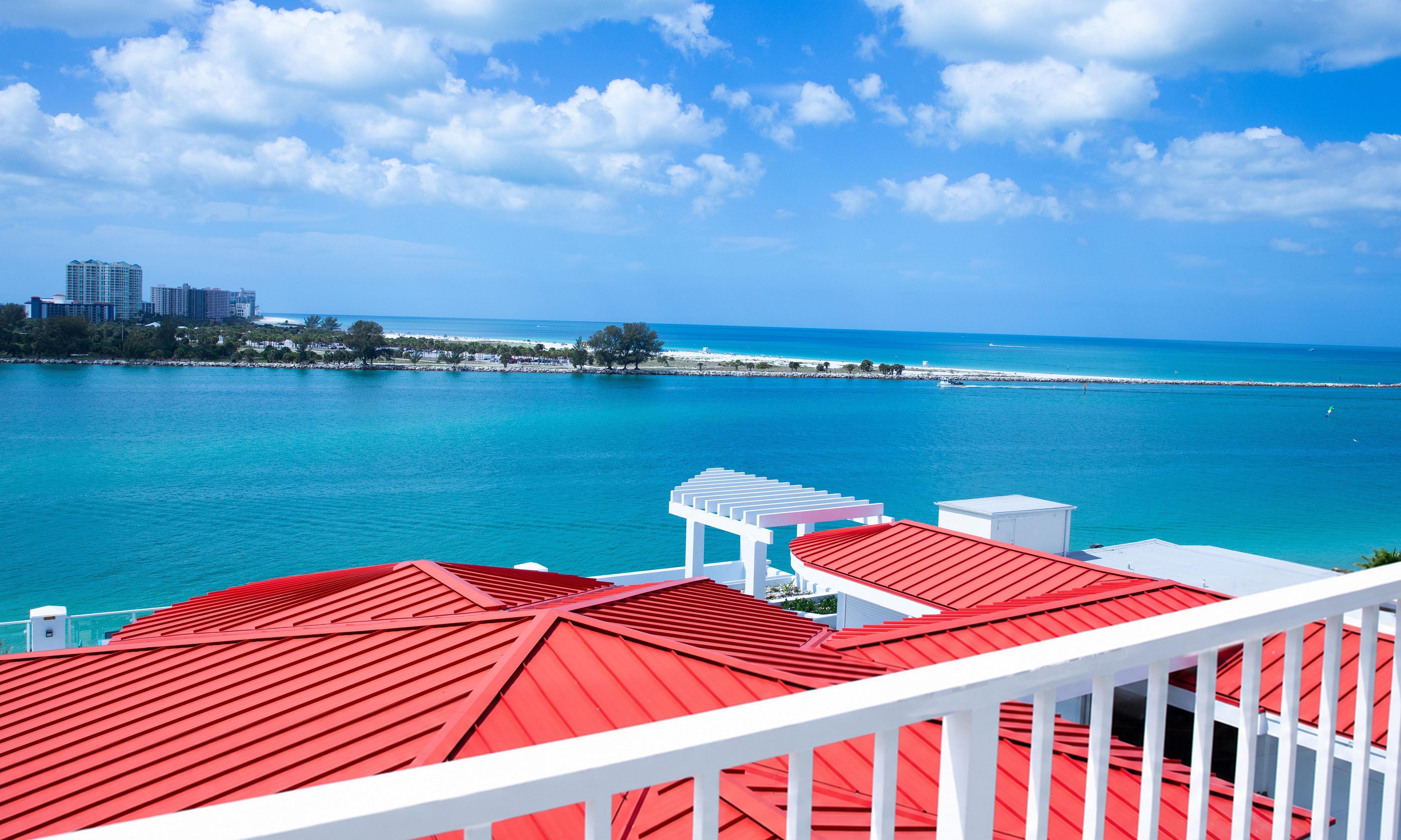 Une vue sur la côte, avec un ciel dégagé, un bâtiment au toit rouge et une balustrade blanche.