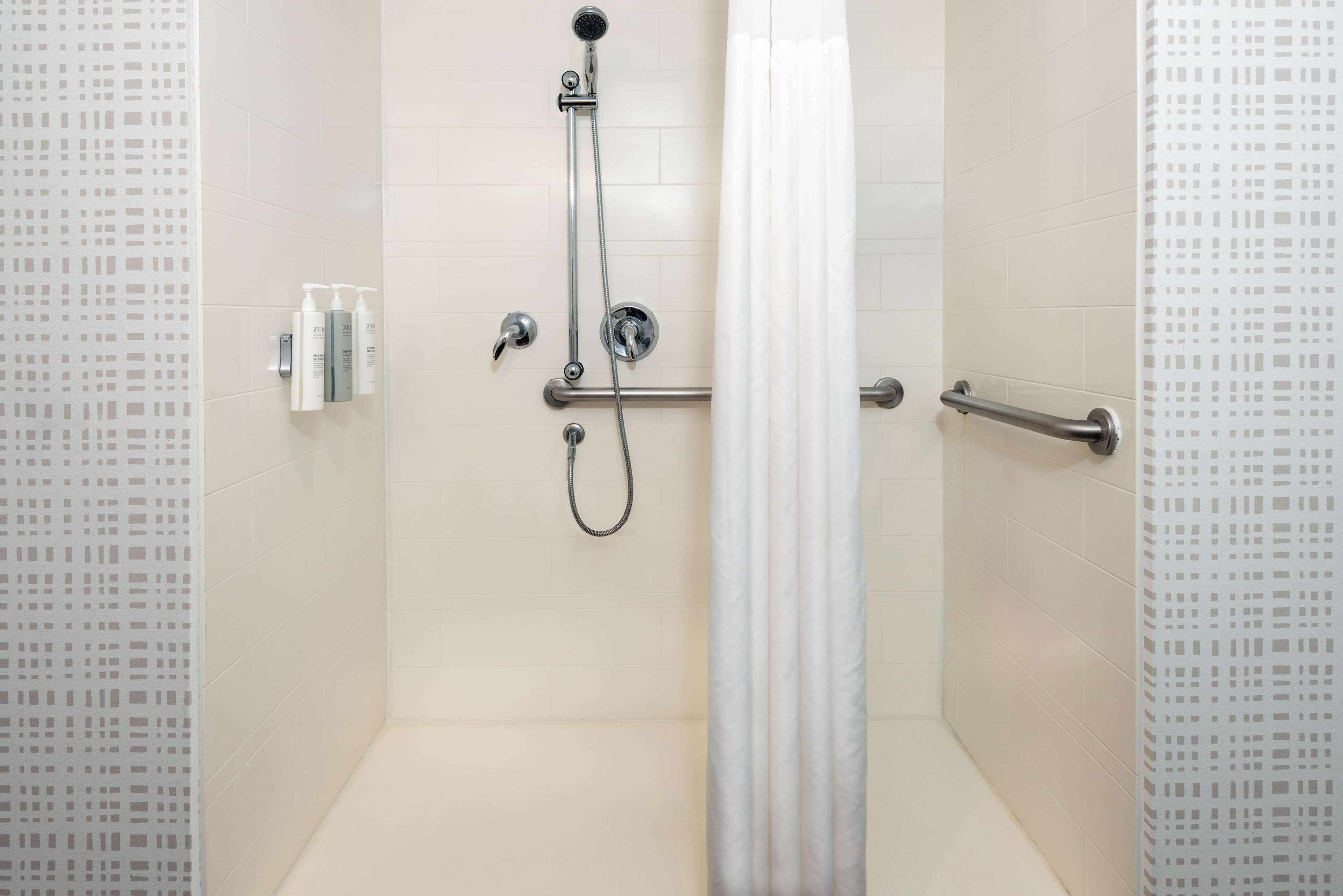 Una ducha moderna con un cabezal de ducha manual, un accesorio de ducha manual y un panel de control.