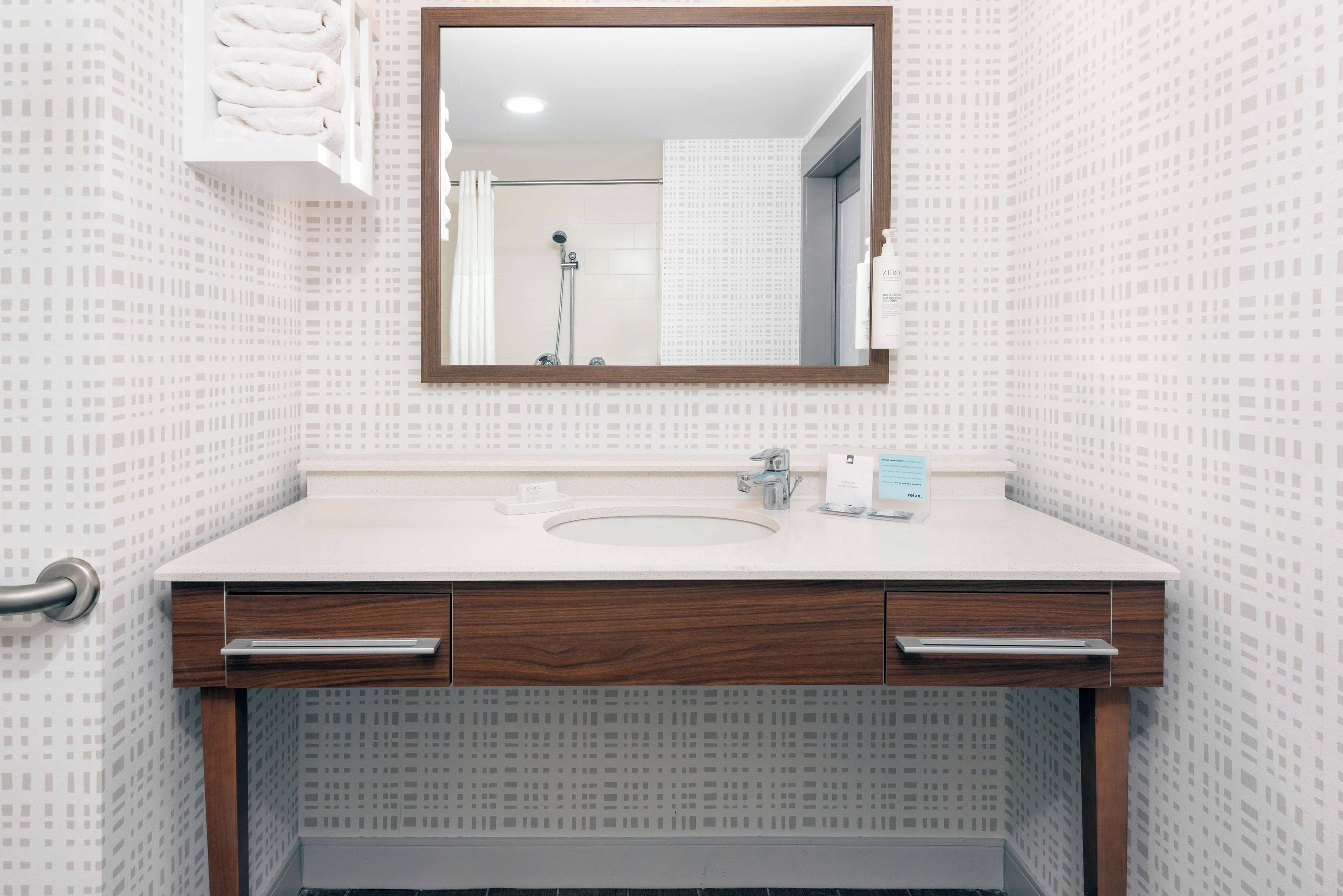 Une salle de bain avec un lavabo blanc, un meuble-lavabo en bois et un miroir.